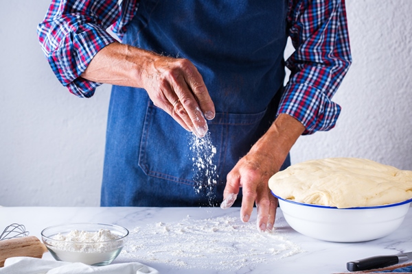 baking eating at home healthy food and lifestyle concept senior baker man cooking kneading fresh dough with hands rolling with pin spreading the filling on the pie on a kitchen table with flour 5 - Французский багет