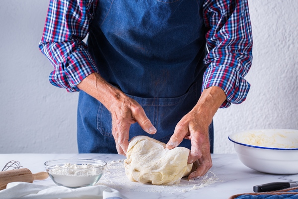 baking eating at home healthy food and lifestyle concept senior baker man cooking kneading fresh dough with hands rolling with pin spreading the filling on the pie on a kitchen table with flour 6 - Французский багет