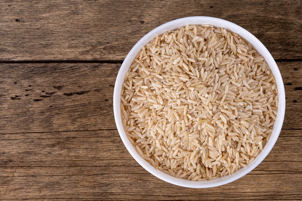 brown raw rice groats in white bowl isolated on wooden background - Сочиво рисовое с миндалём и миндальным молоком