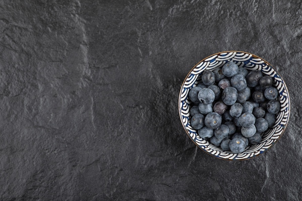 ceramic bowl of delicious ripe blueberries on black surface - Черничный суп