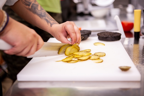 chef slices pickles for delicious burger in restaurant food preparation - Рассольник из рыбы