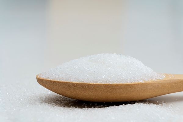 close up scoop with white sand and lump sugar on wooden background - Квас из плодов шиповника