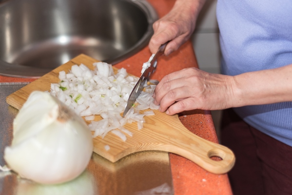 close up view of senior woman hand cutting onion shallow dof selective focus on the hand - Суп-пюре из гороха с гренками