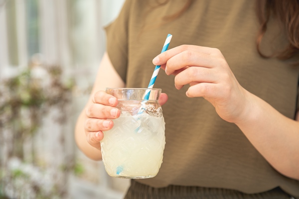 closeup a glass of lemonade in female hands - Квас лимонный