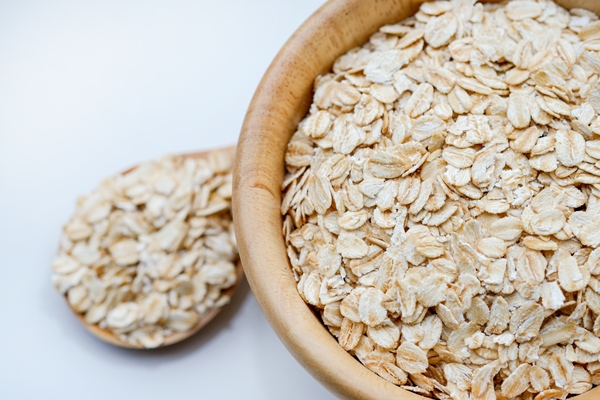 closeup rolled oats in a wooden cup and spoon on white background is a healthy whole grain food - Суп овсяный без масла