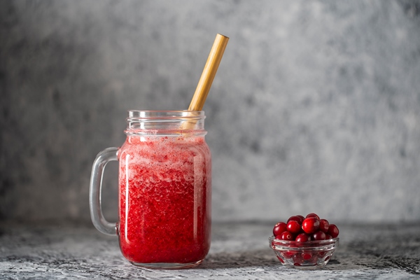 cranberry and cowberry smoothie in mason jar with bamboo straw fresh organic red smoothie in glass mug on table close up refreshing summer fruit drink the concept of healthy eating copy space - Посадский квас