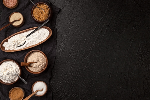 different types of flour in wooden bowls on black table top view of flour and rolling pin with copy space - Агапьин квас