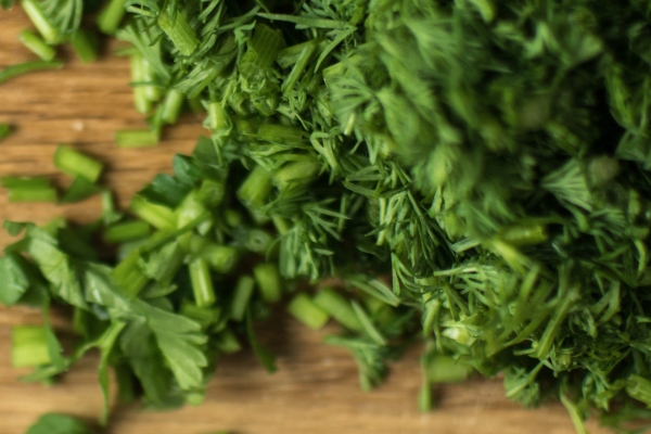 finely chopped greens on a chopping board - Суп с картофелем по-румынски