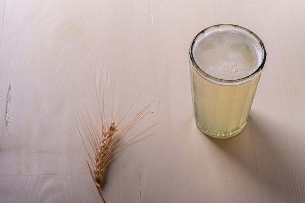 fresh cold drink beverage frothy kvass in faceted glass on white wooden wall near with ear of wheat - Квас с дрожжами (болгарский рецепт)