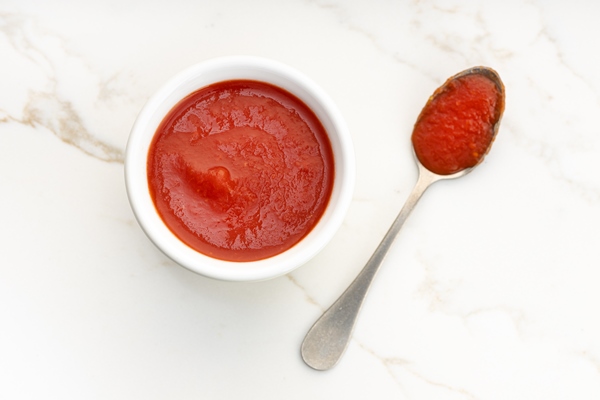 fresh tomato sauce on bowl and spoon on white marble table - Розовые драники