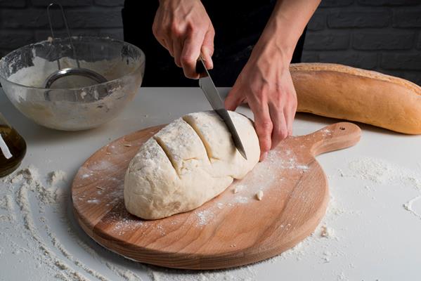 high angle baker slicing dough - Постный овсяный хлеб