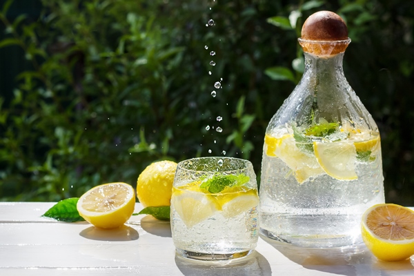 homemade lemonade with lemon mint and ice cubes in a glass pitcher on the white wood table with lemons - Нащёкинский квас