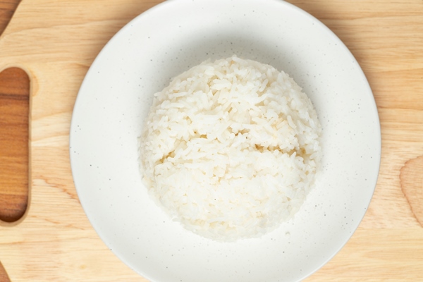 jasmine rice is arranged in a round shape on a white bowl that is placed on a wooden - Сочиво из риса с корицей