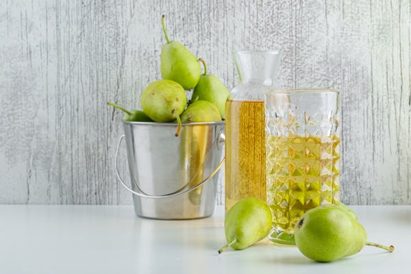 pears with drink in a mini bucket on white and grungy wall side view - Грушевый квас