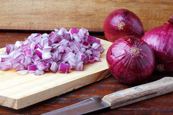 portion of chopped raw red onions over rustic wooden table close up view - Драники с овсяными хлопьями
