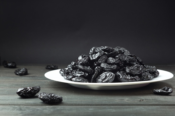 prunes in a plate on a black background dried fruits - Постный суп из чернослива