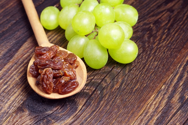raisins in spoon and brush of grape on old wooden table - Черничный суп
