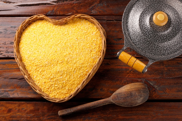 raw cornmeal flour used in polenta in wooden bowl over rustic wooden table - Кумал (квас по-осетински)
