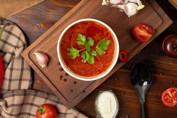 red tomato borsh vegetable soup in disposable cup bowl served with green vegetables - Щи красные