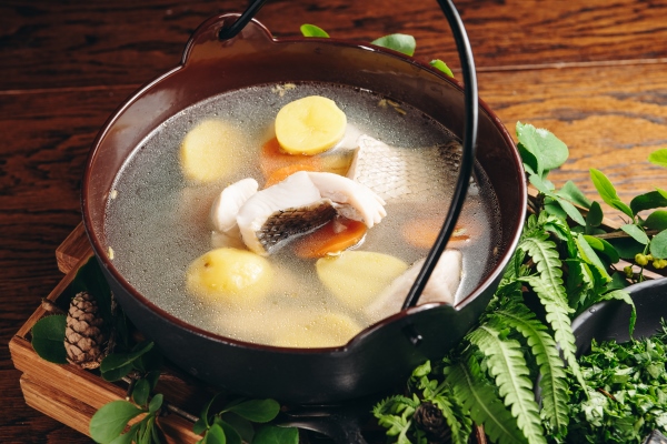 russian traditional fish soup in a bowl ukha served with ember and vodka on wooden board fish broth traditional cuisine in russia - Уха рыбацкая