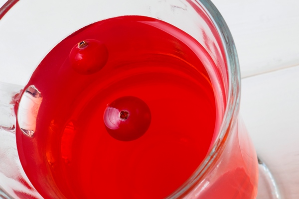 selective focus on cranberries floating in a fresh drink in a glass cup - Августинин квас