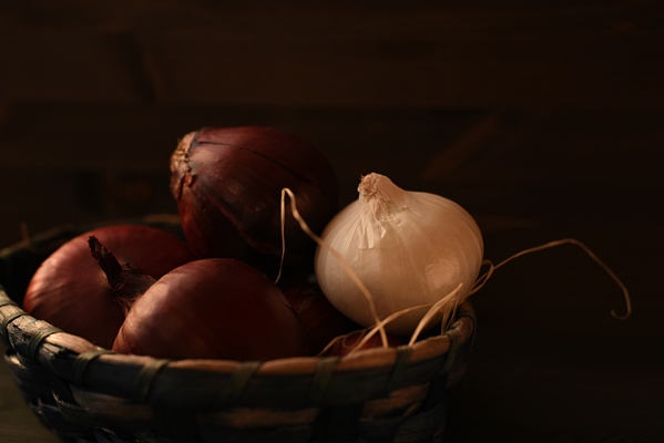 several heads of red spanish onion and one white bulb are folded into a wicker basket dark brown background - Похлёбка постная с грибами