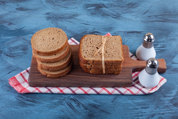 sliced rye bread on a board on towel on the blue surface - Квас золотистый из моркови