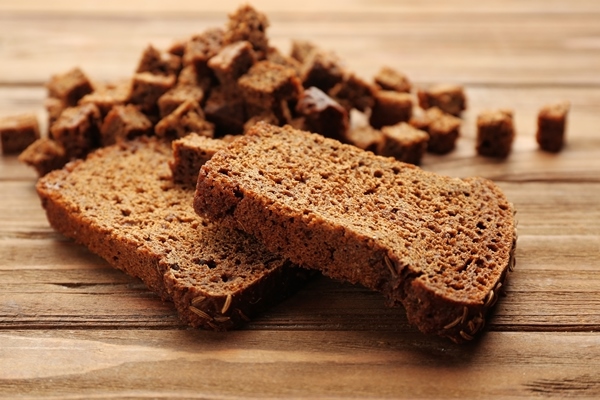 sliced rye bread with seeds and croutons on wooden background - Квас-сырец (украинская кухня)
