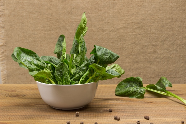 spinach in white bowl light wooden background top view - Щи зелёные из одного щавеля или пополам со шпинатом