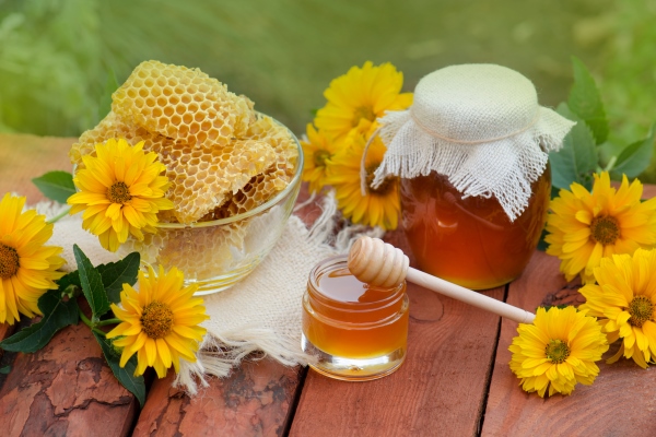 sweet honey in the comb jars of honey bee honeycomb on wooden table with flowers background natural organic healthy food concept - Клюквенный квас с можжевеловыми ягодами
