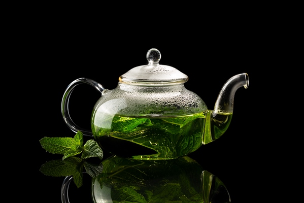 teapot with brewed mint tea on a black background - Квас душистый с мятой