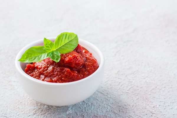 tomato paste and basil leaves in a bowl on a light background vegetable and vegetarian food vitamins and detox diet copy space - Солянка рыбная сборная