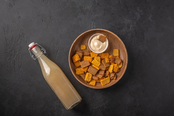 top view homemade traditional russian light rye kvass in bottle and crackers on dark wooden - Федотьин квас-щи