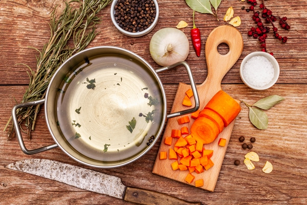 transparent duck broth in pan with fresh ingredients traditional bouillon for healthy dishes spices vegetables old wooden table 1 - Солянка рыбная сборная