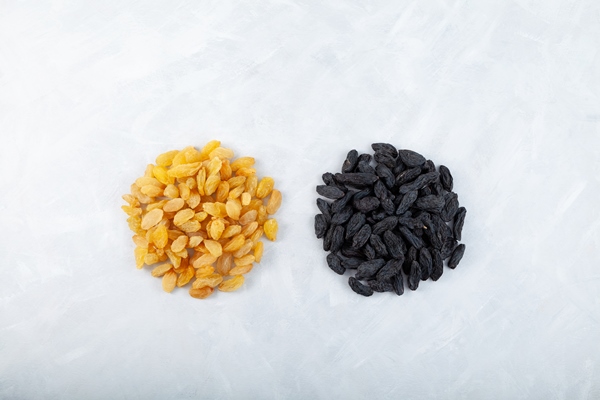 two handfuls of raisins from dark and golden grapes on grey background top view - Сочиво из перловки с узваром