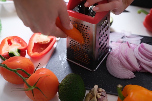 woman grates vegetables in kitchen preparing vegetables for lunch meals - Суп из свежих помидоров с капустой