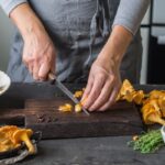 woman is cutting fresh chanterelles on the boards in the kitchen - Маринованные лисички