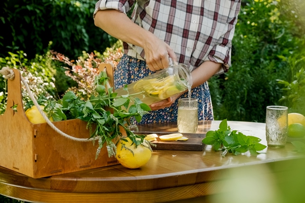 woman pouring homemade lemonade drink into glass in summer garden - Екатерининский квас