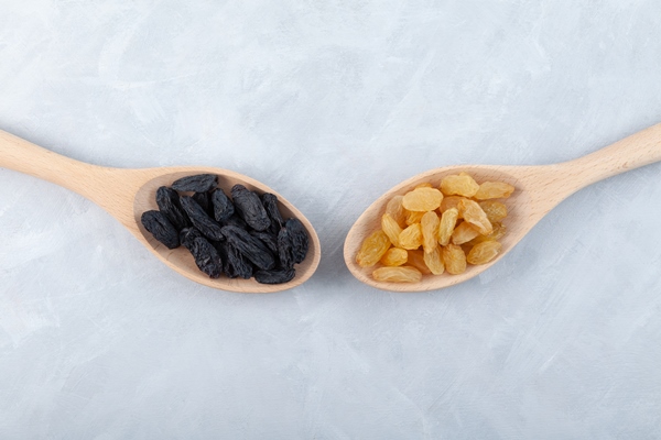 yellow raisins and black raisins in wooden spoons on grey background top view dried grapes fruit - Белгородский лимонный квас