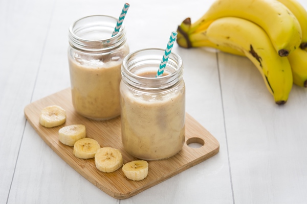 banana smoothies in jar on white wooden table - Постный смузи из банана и кешью