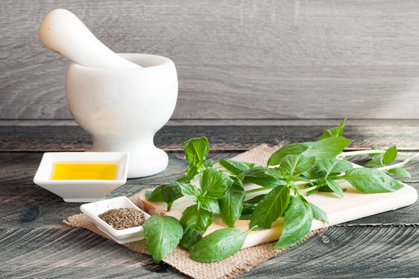 basil on a chopping board and olive oil on a wooden background - Постная яблочная аджика с базиликом