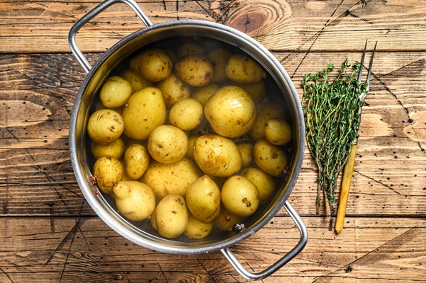 boiled baby potatoes in a saucepan wooden background top view - Картофель "в мундире"