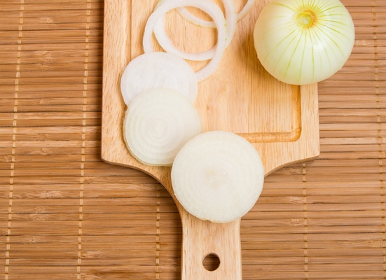 bulb onions sliced on wooden cutting board top view - Слоёный салат с шампиньонами и черносливом