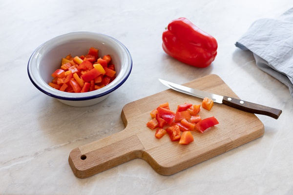 chopped red bell pepper with a knife on a cutting board - Постная яблочная аджика с базиликом