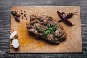 cooked pork meat on a chopping board on a table with pepper garlic onion and spices 1 - Правила составления меню