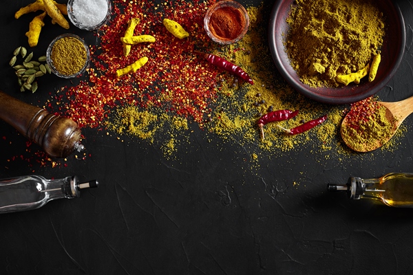 cooking using fresh ground spices with big and small bowls of spice on a black table with powder spillage on its surface overhead view with copyspace still life flat lay top view - Постный соус чатни из яблок