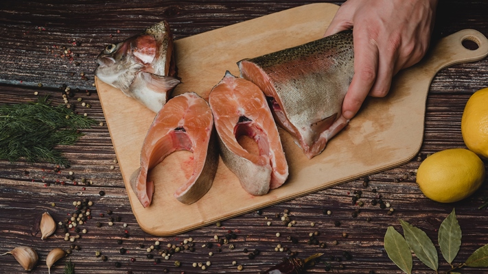 cut into pieces red fish trout on a wooden board - Рыбный бульон из целой рыбы