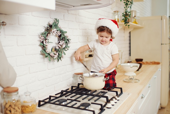 cute little girl in santa hat preparing cookies in the kitchen at home sits on the kitchen table and helps mom prepare a festive christmas dinner - Готовим гречневую кашу вместе с детьми