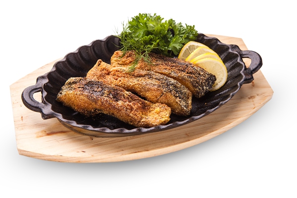 fried fish slices of fried fish in batter served with lemon and lettuce in a black pan on a wooden board white background - Тушёная рыба, постный стол