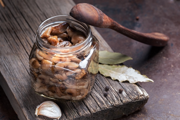 glass jar with pickled forest honey agarics wooden spoon and spices on old wooden board - Салат с маринованными грибами и корейской морковью